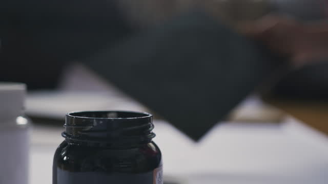 Woman artist dips a brush into a jar of black paint for drawing
