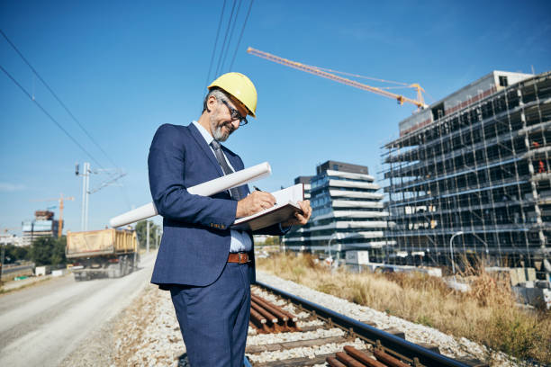 istock senior businessman architect helmet construction site building architecture writing notebook protective workwear blueprint plan 1388013023