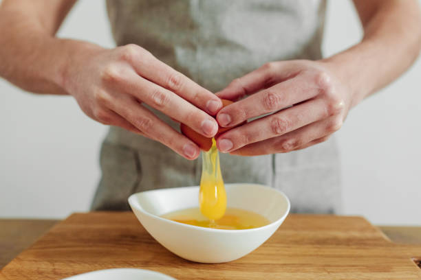 istock Man in apron cooking, in progress. Broken egg in hand 1388013545