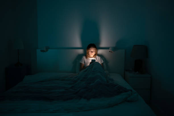 Sleepy woman lying in bed using smartphone late at night, can not sleep. Insomnia, addiction concept Sleepy exhausted woman lying in bed using smartphone, can not sleep. Insomnia, addiction concept. Sad girl bored in bed scrolling through social networks on mobile phone late at night in dark bedroom. insomnia stock pictures, royalty-free photos & images
