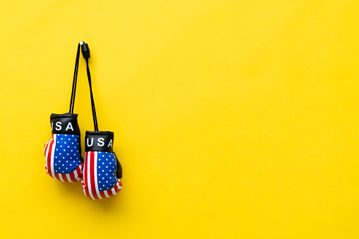 Boxing glove with American flag on yellow background.