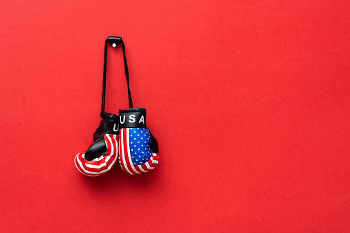 Boxing glove with American flag on red background.