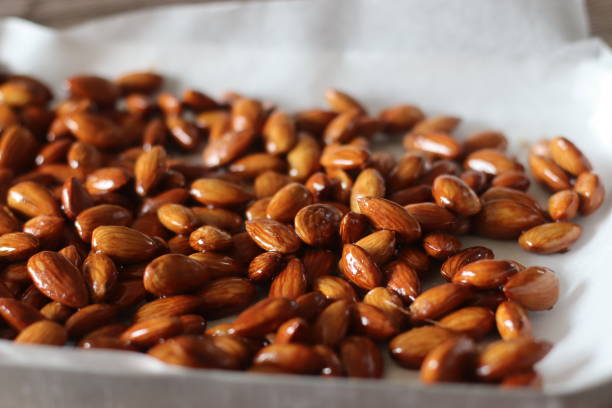 Candied almonds. Toasted almonds coated with caramel syrup Candied almonds. Toasted almonds coated with caramel syrup. Shot inside the baking tray silver platter stock pictures, royalty-free photos & images