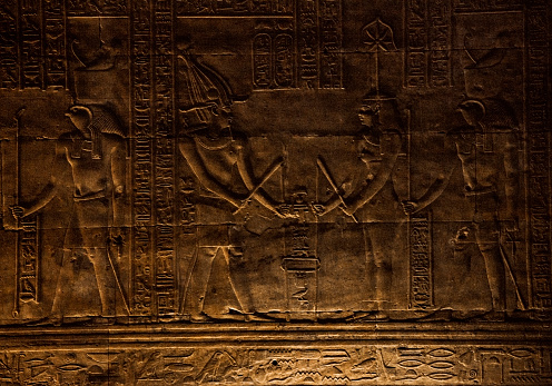 Pharaoh Ptolemy III Euergetes and the goddess Seshat “Stretching the Cord” Hieroglyphic at the Temple of Edfu in Edfu, Egypt. “Stretching the Cord” is an ancient Egyptian ritual to determine the proper astronomical orientation of a temple.