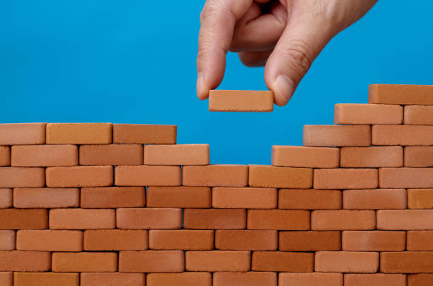 istock Man putting toy brick onto a wall 1388022919