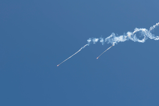 Two false heat targets (infrared countermeasure) flies in clear blue sky. Copy space for your text. Military industry theme.