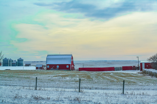 Red farm building in rural Alberta, with a wintery sunset backdrop, taken in November of 2019.