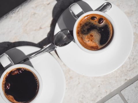 Dos tazas de café aromático de pie sobre una mesa vacía photo