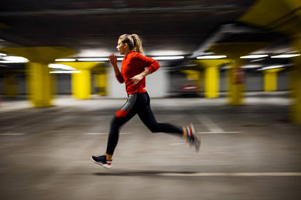 Young woman runner running in parking lot