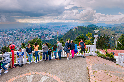 Bogotá, Colombia - July 16, 2017: Local Colombian pilgrims and tourists seen on the Andes peak of Guadalupe in front of the Church dedicated to the Virgin of Guadalupe. It is considered a place of pilgrimage in South America. In the background is the mountain peak of Monserrate and far below at almost 2,400 feet below, is the Altiplano Cundiboyacense and the capital city of Bogotá. The people are standing at an altitude of over 11,000 feet above mean sea level. Copy Space.