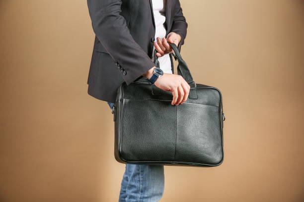 istock man holds leather briefcase close up, studio photo shot 1388033600