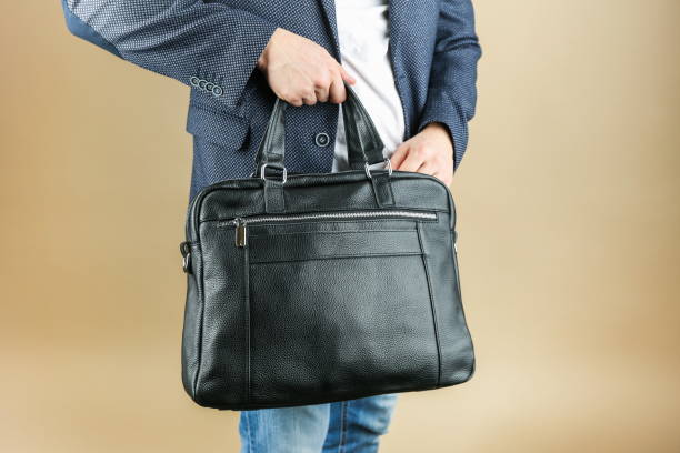 istock man holds leather briefcase close up, studio photo shot 1388033780