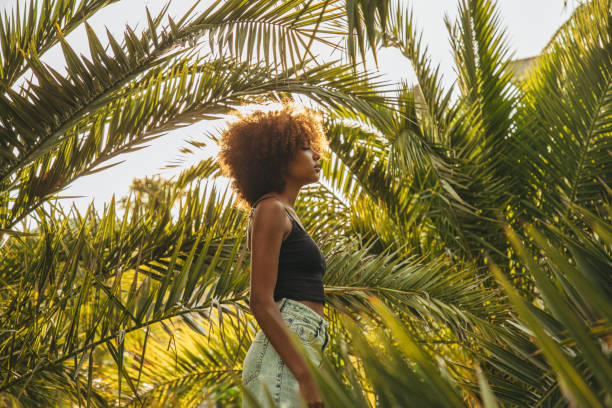 istock Pretty young afro woman among palm trees 1388035972