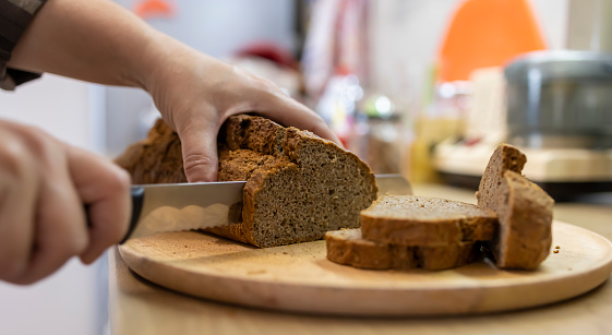 Shot of an unrecognizable woman cutting a brown bread