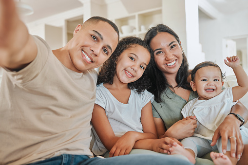 Foto de una hermosa familia tomándose una selfie juntos mientras se unen en el sofá de casa photo