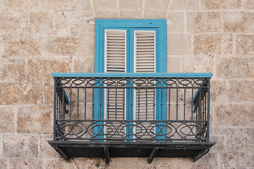 Typical balcony in Cuban Baroque style in Old Havana, Cuba. Wrought railings, door with wooden blinds.Travel, architecture concept