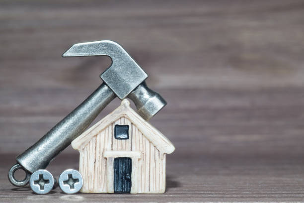 istock Hammer and screws by a house model 1388042126