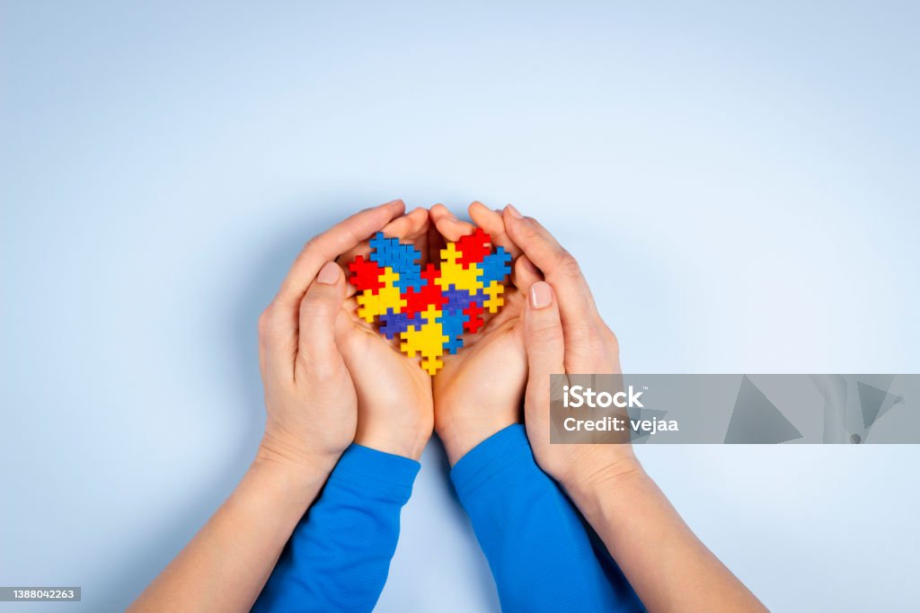 World autism awareness day concept. Adult and child hands holding puzzle heart on light blue background. Top view World autism awareness day concept. Adult and child hands holding puzzle heart on light blue background. Top view. Autism Stock Photo