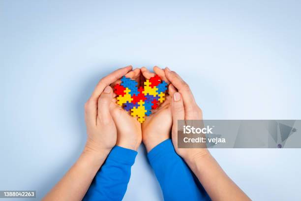 World Autism Awareness Day Concept Adult And Child Hands Holding Puzzle Heart On Light Blue Background Top View Stock Photo - Download Image Now