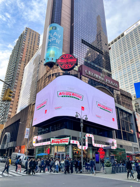 vue verticale du nouveau times square krispy kreme phare d’un théâtre de beignets unique en son genre, montrant comment les friandises sucrées sont fabriquées. - krispy kreme photos et images de collection