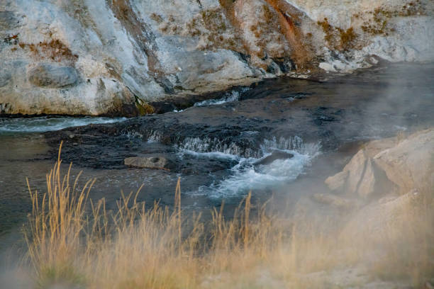 Cascade (waterfall) on the Firehole River with steam rising from adjacent geysers in the Old Faithful Geyser Basin in Yellowstone National Park in Wyoming near Montana in the United States of America (USA).