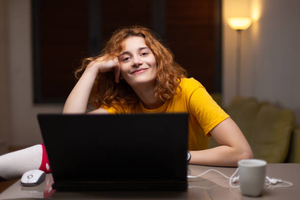 istock Cute girl working on a computer in living room. Student taking online course. Home education concept 1388054854