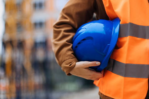 Unrecognizable female construction worker standing in a building site while holding a helmet