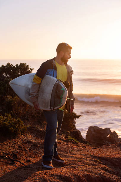 istock man with surfboard watching the sunset by the sea 1388068244