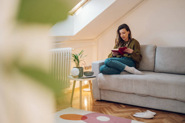 istock Woman reading a book while sitting on the couch at home 1388068617