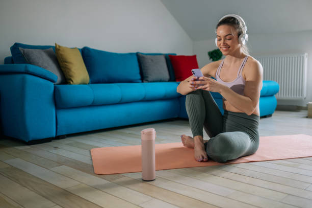 istock Woman using headphones and a smartphone while training at home 1388068627