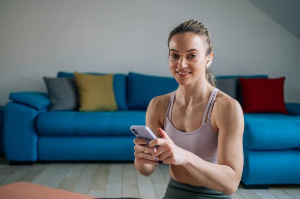 istock Woman using airpods and a smartphone while training at home 1388068633