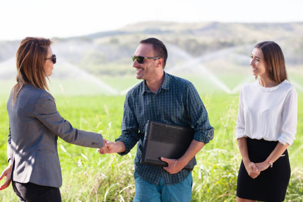business people shaking hands in a green field with agriculture irrigation system. - commercial sprinkler system imagens e fotografias de stock