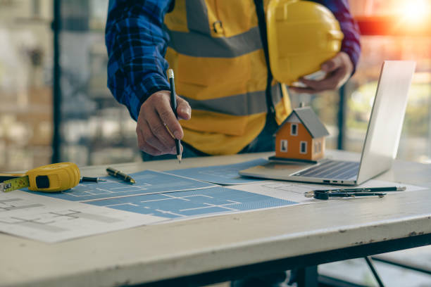 istock Young engineers and architects design, plan, measure the layout of blueprints with tabletop tools in construction concepts with hats and houses on the table. 1388078668