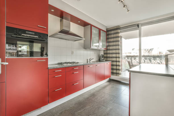 The interior of a small kitchen in red tones with a marble countertop in a cozy house