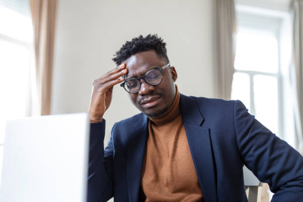 istock Stressed tired African American man touching temples, suffering from headache after long hours work, overworked overwhelmed businessman sitting at desk, feeling unwell 1388108867
