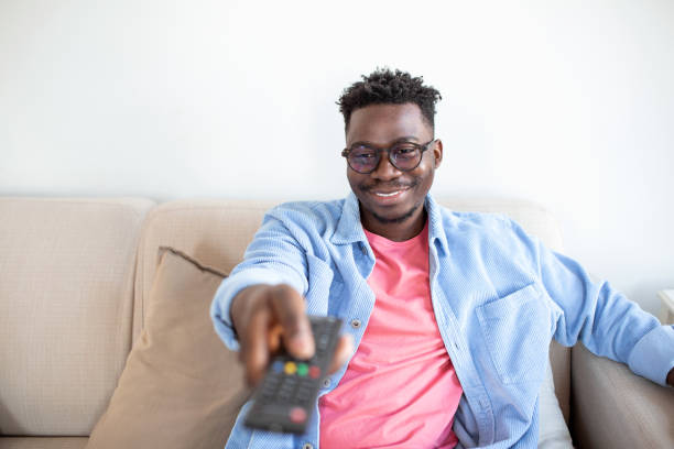 istock Excited African American Man Pointing Television Controller To Camera Switching Channels Watching TV . Television Programming Advertisement. Selective Focus 1388108994
