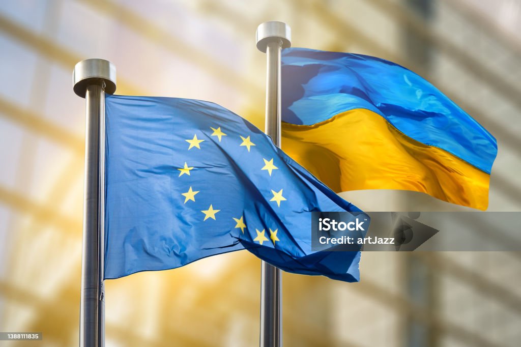 Flags of European Union and Ukraine Flags of European Union and Ukraine against European Parliament bulding in Brussels, Belgium European Union Stock Photo