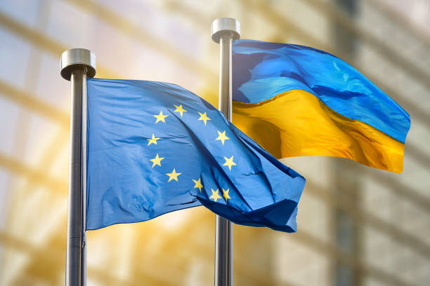 Flags of European Union and Ukraine Flags of European Union and Ukraine against European Parliament bulding in Brussels, Belgium teamwork slogan stock pictures, royalty-free photos & images