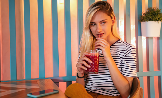 Young girl having a good morning healthy smoothie drink made of super foods. People health concept