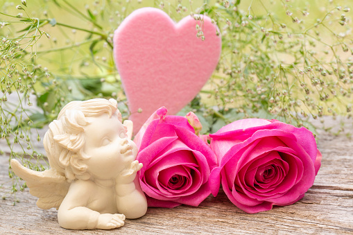 Pink rose flower arrangement with heart and angel figurine for holidays
