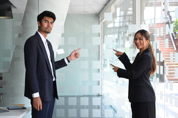 istock Executive businesspeople in formal suit presenting, pointing at copy space for your advertise information content. 1388114966