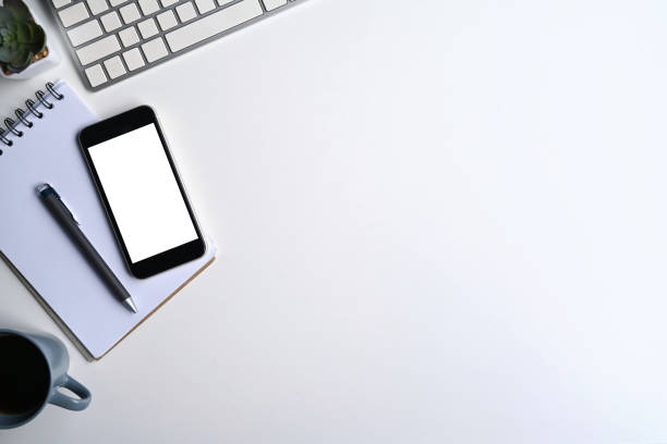 istock Top view mobile phone, notebook, coffee cup and wireless keyboard on white office desk. 1388115044