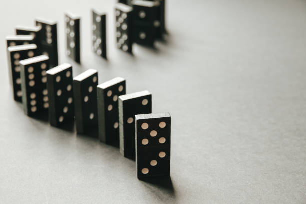 istock Black dominoes chain on white table background 1388115151