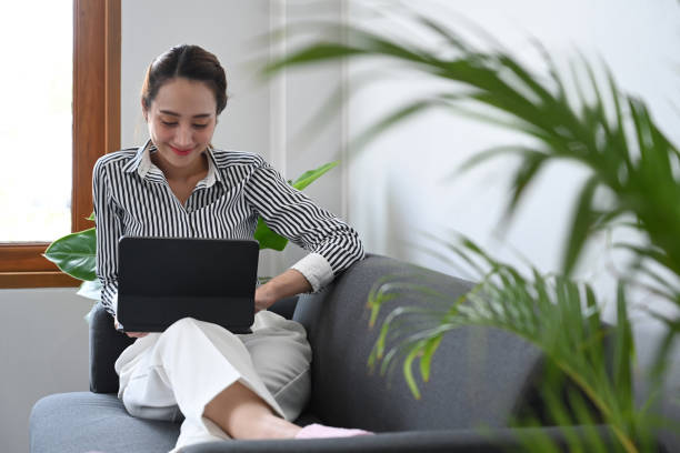 istock Pleasant young woman sitting on comfortable sofa and using digital tablet. 1388116294