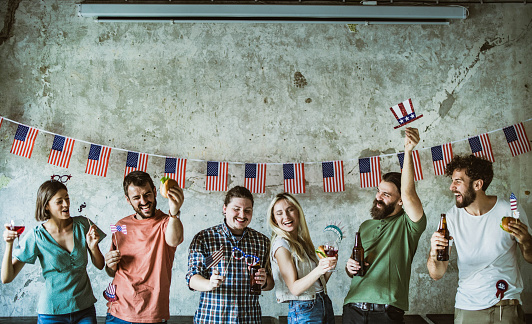 Large group of cheerful colleagues celebrating Independence day on a party in the office. Copy space.