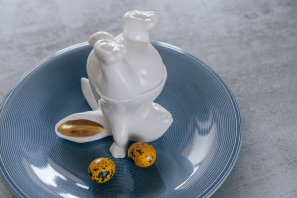 istock Easter rabbit, bunny porcelain decoration and two yellow eggs on a blue plate. Easter table decorations. Spring holidays concept, pastel background. 1388122130
