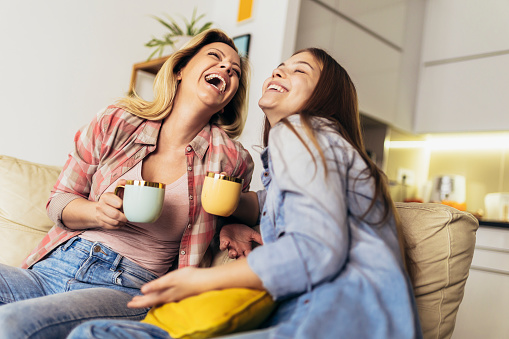 Mother and daughter drink tea or coffee at home.