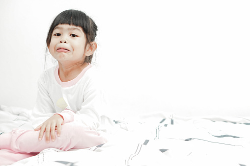Adorable cute asian little girl on her bed. Waking up making face expression. Stay Positive Concept.