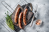 Grilled beef and lamb meat sausages with rosemary herbs on grill. Gray background. Top view