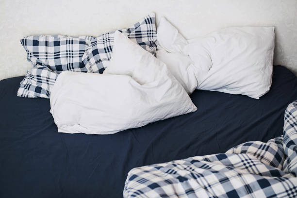 istock Rumpled bedding after sleep. Pillows, sheets and blanket, close up. 1388126897